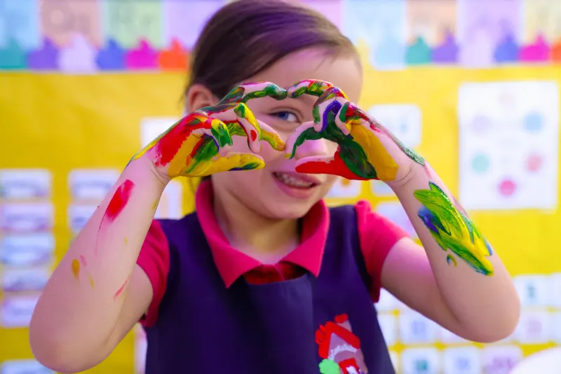 Niña formando un corazón con sus manos pintadas en La Casita Dulce